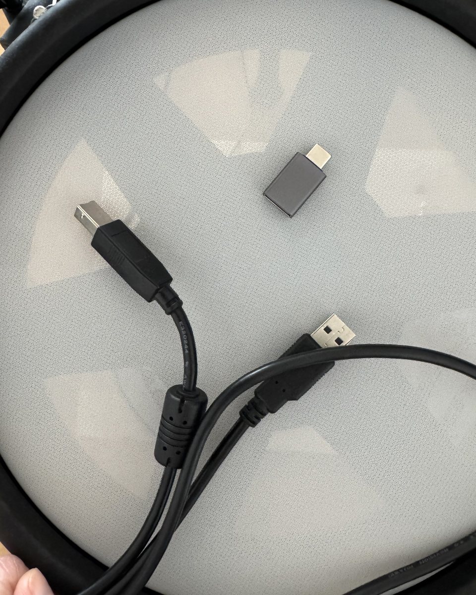 A black USB-A to USB-B cable and a small grey USB-C to USB-A adapter, not yet connected.