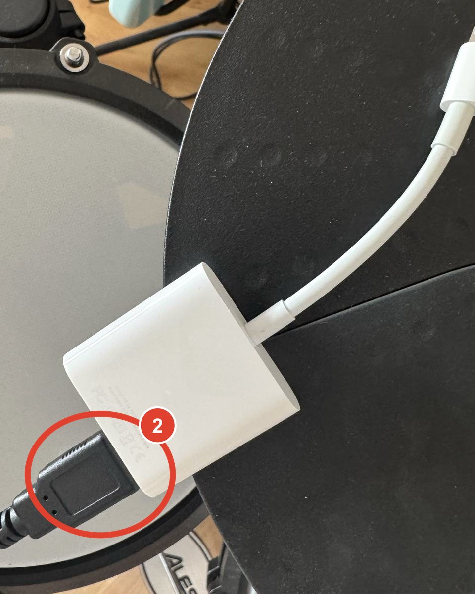 The drum kit USB-A plug inserted into the USB port of the white camera adapter.