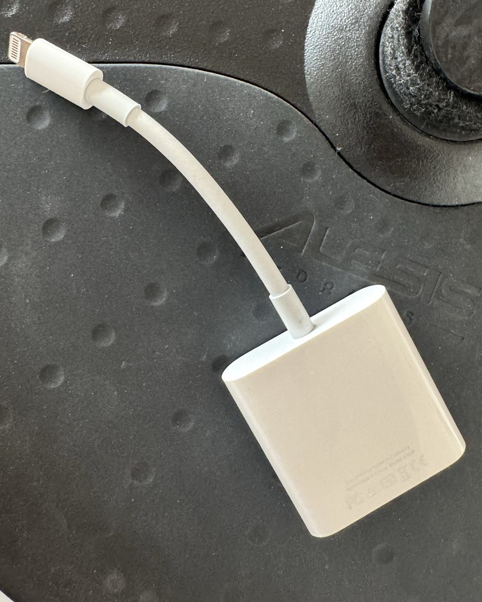 The white Apple Lightning to USB 3 Camera Adapter: a short Lightning cable on a square body with a USB port and a Lightning port.