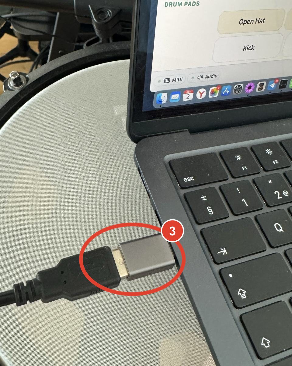 A MacBook on a drum pad with the kit cable connected through the adapter and iQuantize open on the drum pads screen.